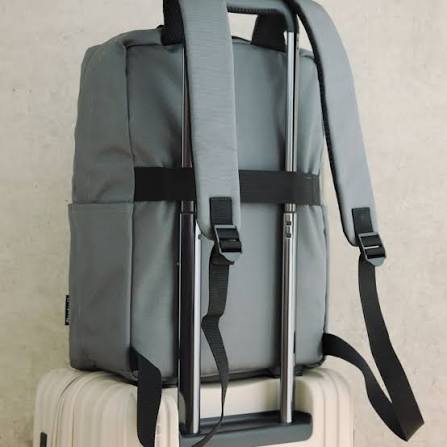 Open cabin backpack with a folded shirt and charger visible next to a closed checked suitcase by an apartment door, shoes lined against the wall, late afternoon light from a side window, 1400x933